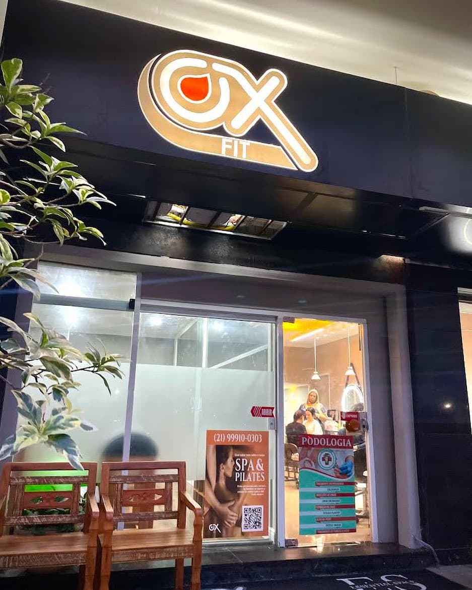 Fachada da Ox à noite, com o logo iluminado sobre a porta de vidro