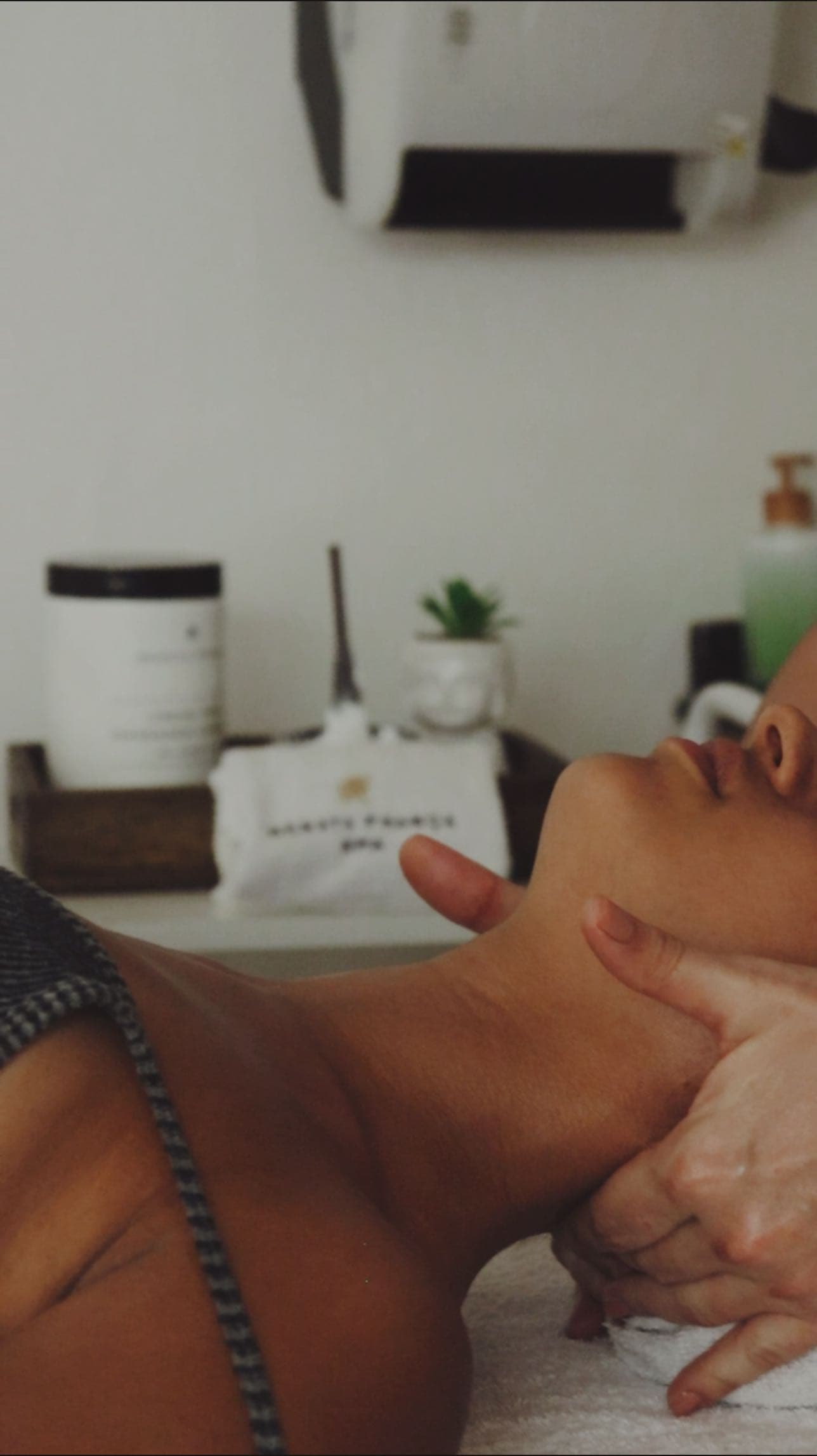 Cliente de olhos fechados recebendo massagem no rosto e no pescoço